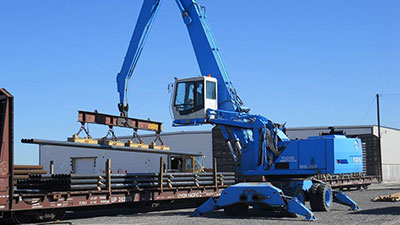 Industrial Crane loading pipe at Adams Industries Storage yard